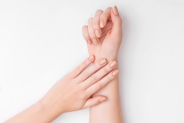 Closeup of hands of a young woman with manicure on nails against white  background