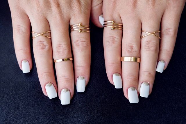 White nail art manicure, hands with fashion gold rings