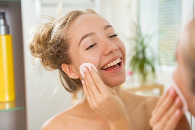 Young beautiful woman cleaning her face skin with cotton pad
