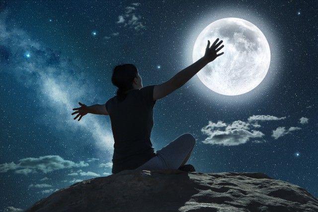 woman raising arms in the moonlight