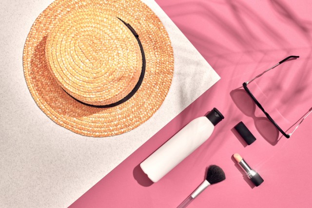 Woman's accessories lying flat on textured paper background. Pink and white pastel colors with copy space around products