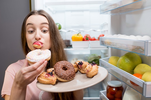 Woman with sweet food near refrigerator