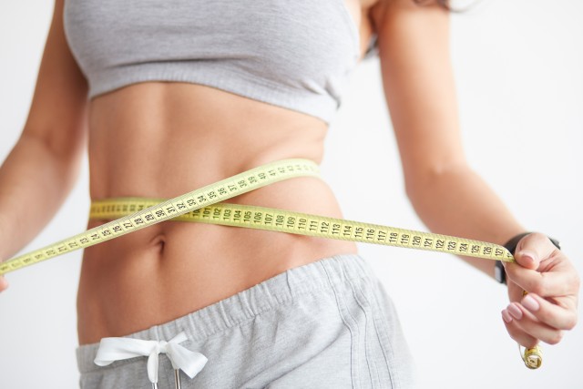 Slim girl with centimeter on white